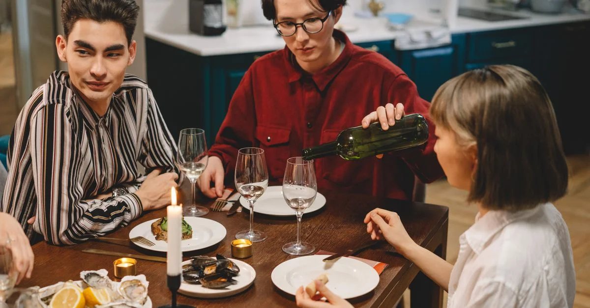 Des amis appréciant un dîner confortable avec du vin et des fruits de mer dans une cuisine moderne.