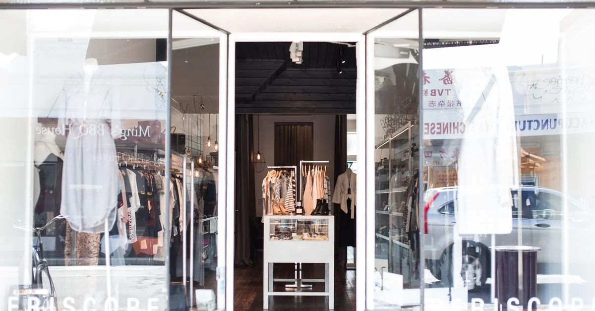 Entrée d'une boutique de vêtements chic avec des vitrines élégantes et des vêtements soigneusement sélectionnés.